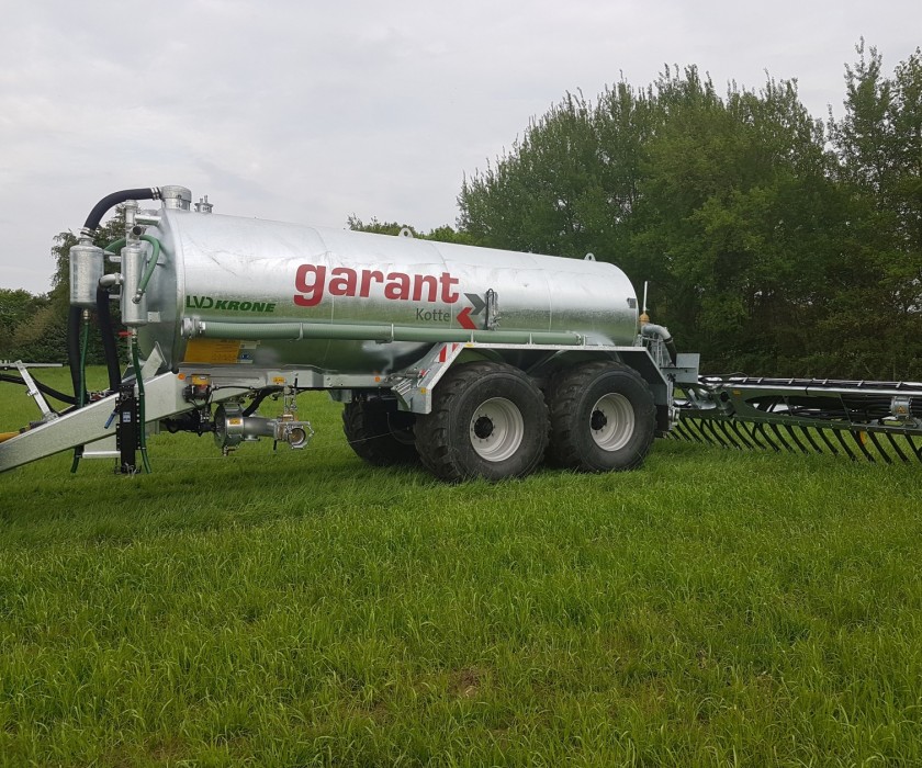 Graues Güllefass von Garant von Krone. Stehend auf einem Feld mit gras. Seitenansicht.